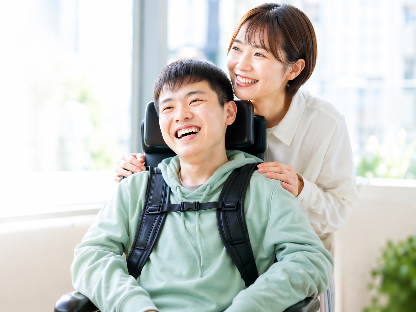 車椅子の男性とそれを支える女性の笑顔